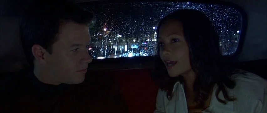 The Truth About Charlie (2002) movie still: medium — A dark, cramped car interior provides the setting as rain streaks the rear windshield. A man…