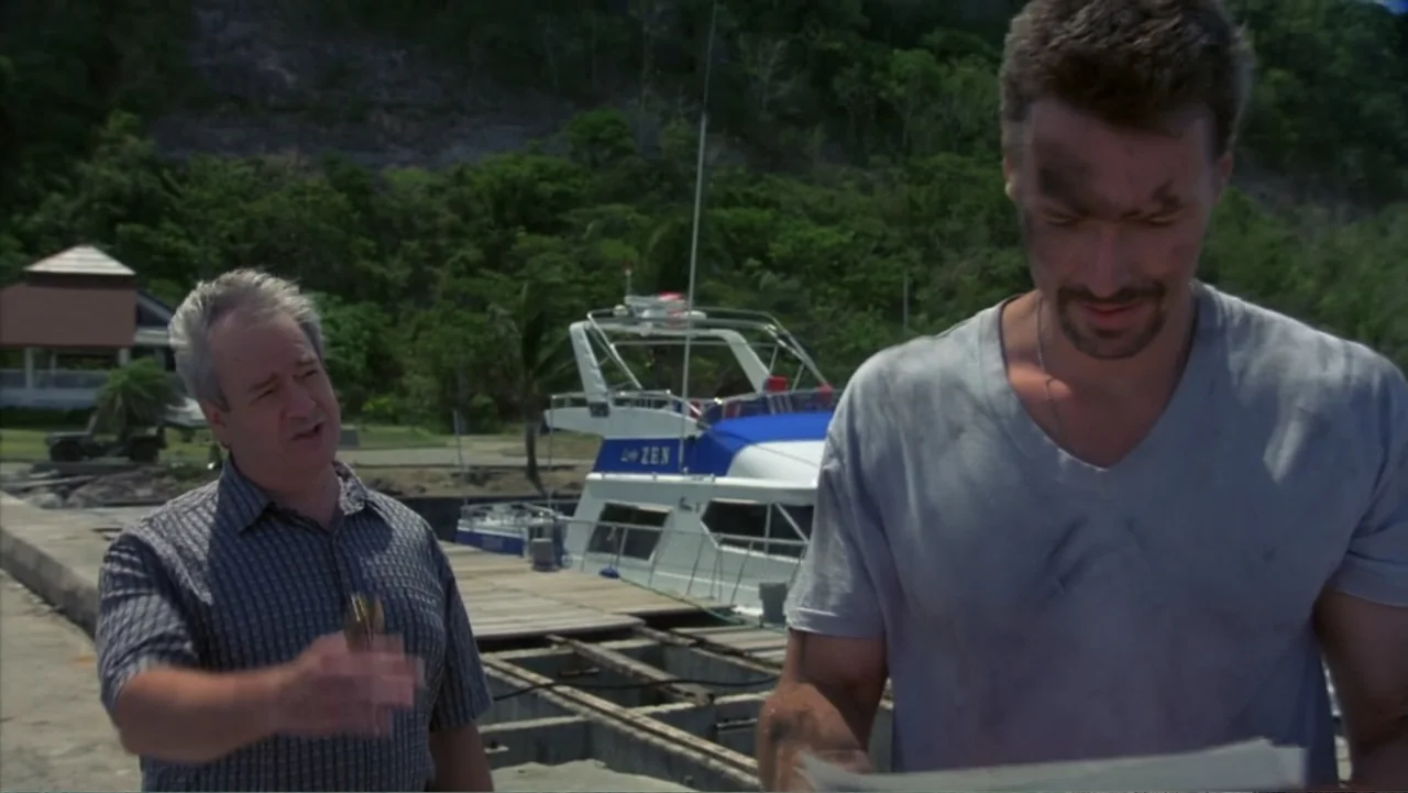 Behind Enemy Lines (2001) movie still: medium — A sunlit concrete pier sits in front of a parked yacht and hillside trees. A man in a checkered…