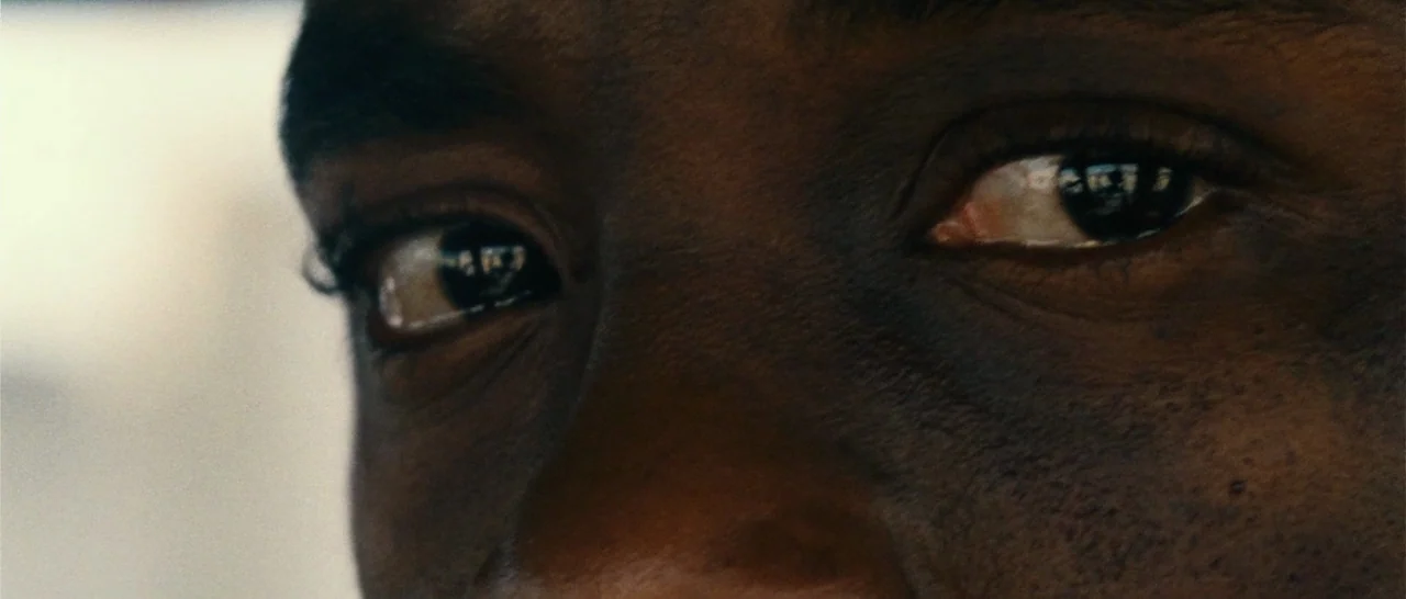 Message From The King (2016) movie still: closeup — A close-up view of a person's eyes inside a vehicle during the day. The subject looks ahead with…