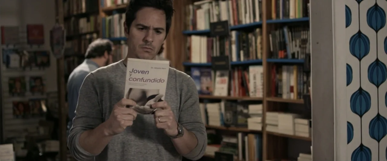 Do It Like An Hombre (2017) movie still: medium — A bookstore interior features floor-to-ceiling shelves packed with various books and colorful…