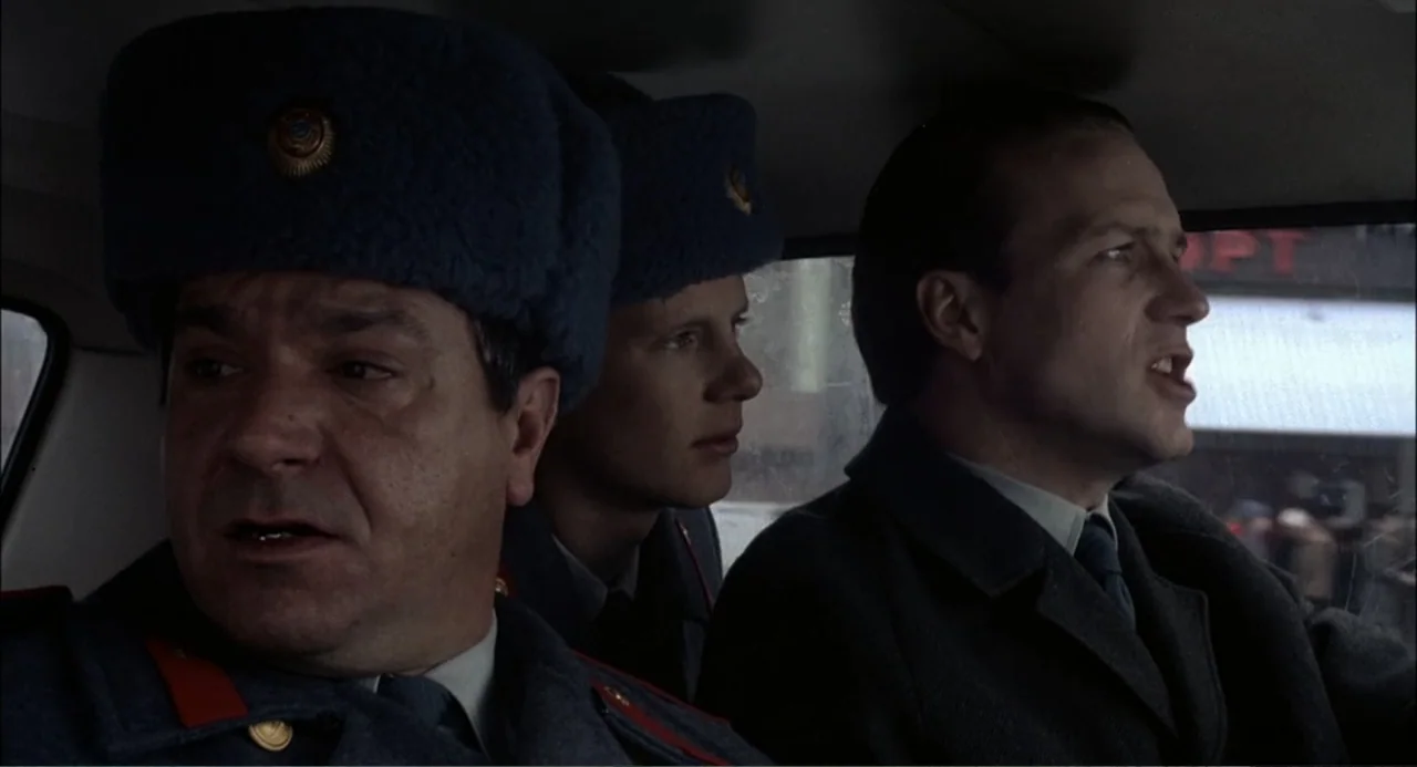 Gorky Park (1983) movie still: medium — A car interior contains three men seated close together in the front and back rows. Two men wear blue…