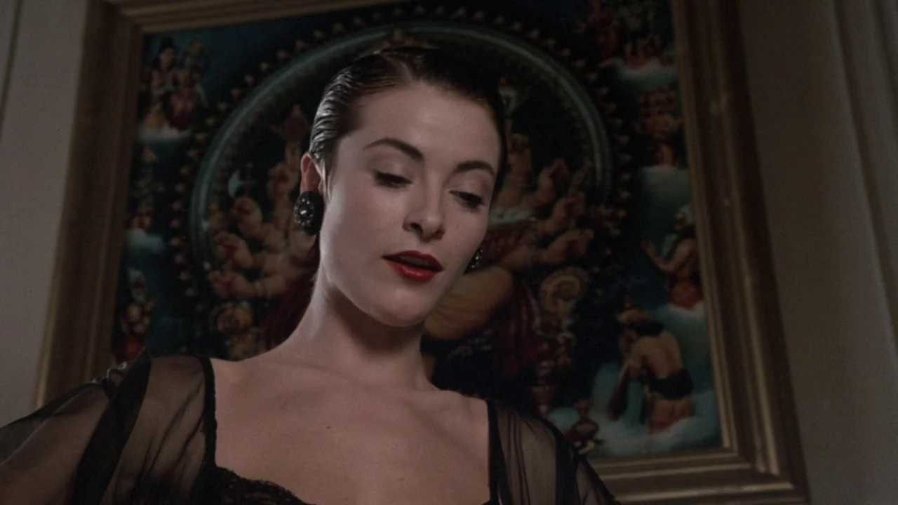 The Lair of the White Worm (1988) movie still: medium — A woman stands indoors in front of a framed painting featuring traditional religious…