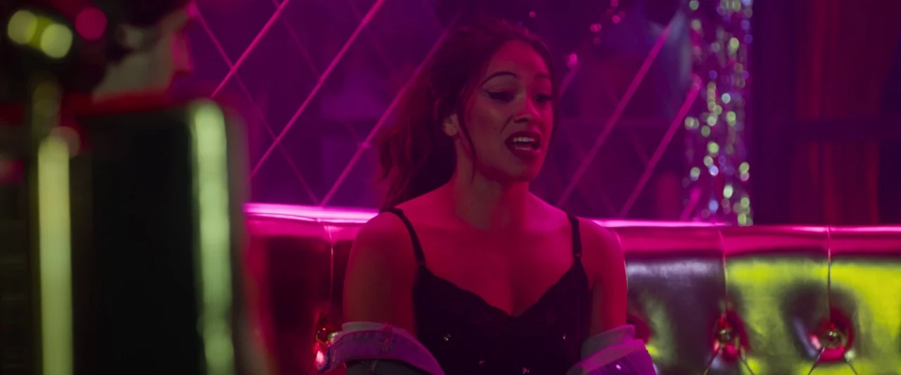 Someone Great (2019) movie still: medium — A dimly lit lounge setting features metallic gold tufted seating and a geometric mirrored wall. A young…