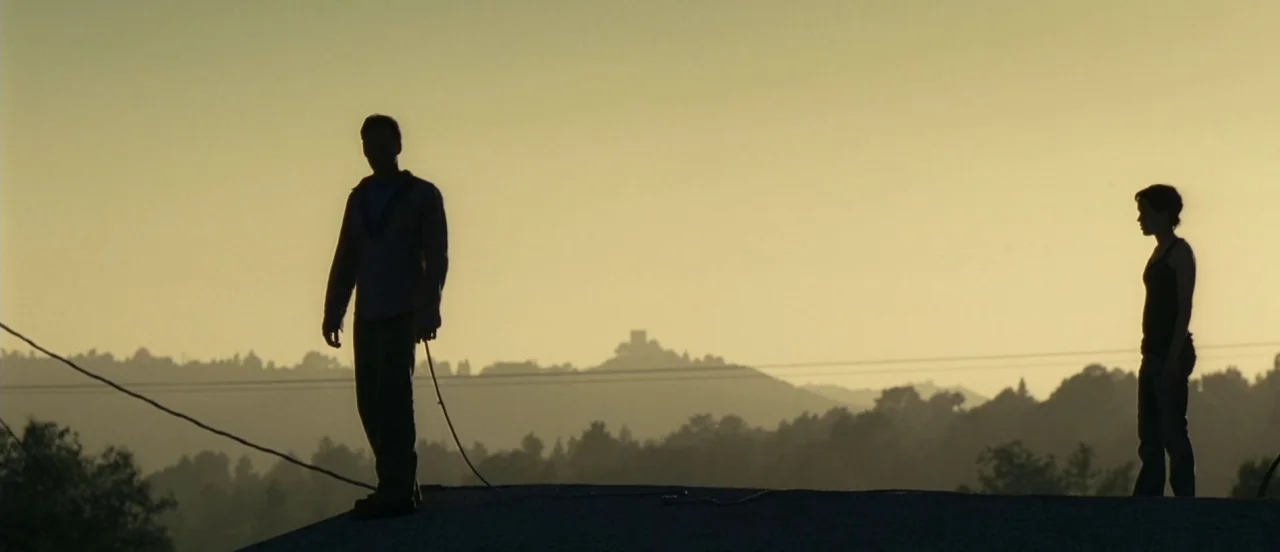 Hard Candy (2005) movie still: wide — A flat roof overlooks a hilly landscape with power lines running across the frame. A man and a woman stand on…