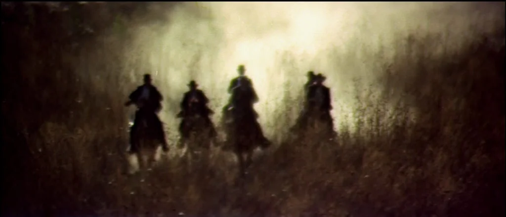 Butch Cassidy and the Sundance Kid (1969) movie still: wide — A group of riders on horseback traverse a dense, dusty field during the day. The…