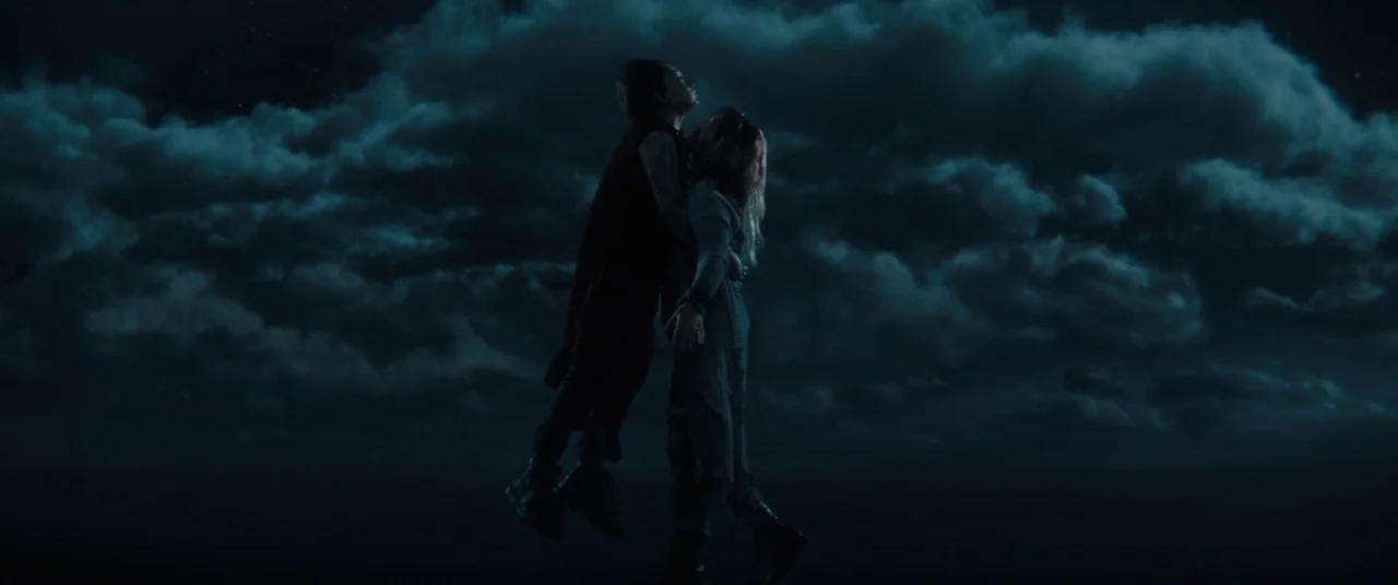 Brightburn (2019) movie still: fullbody — Two individuals float together against a backdrop of thick, dark clouds at night. They are embracing each…