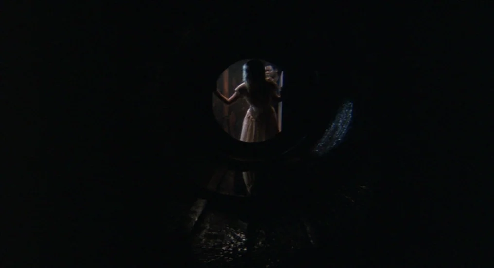 A Nightmare On Elm Street 4: The Dream Master (1988) movie still: wide — The view through a dark, cylindrical pipe looks out toward a lit room. A…