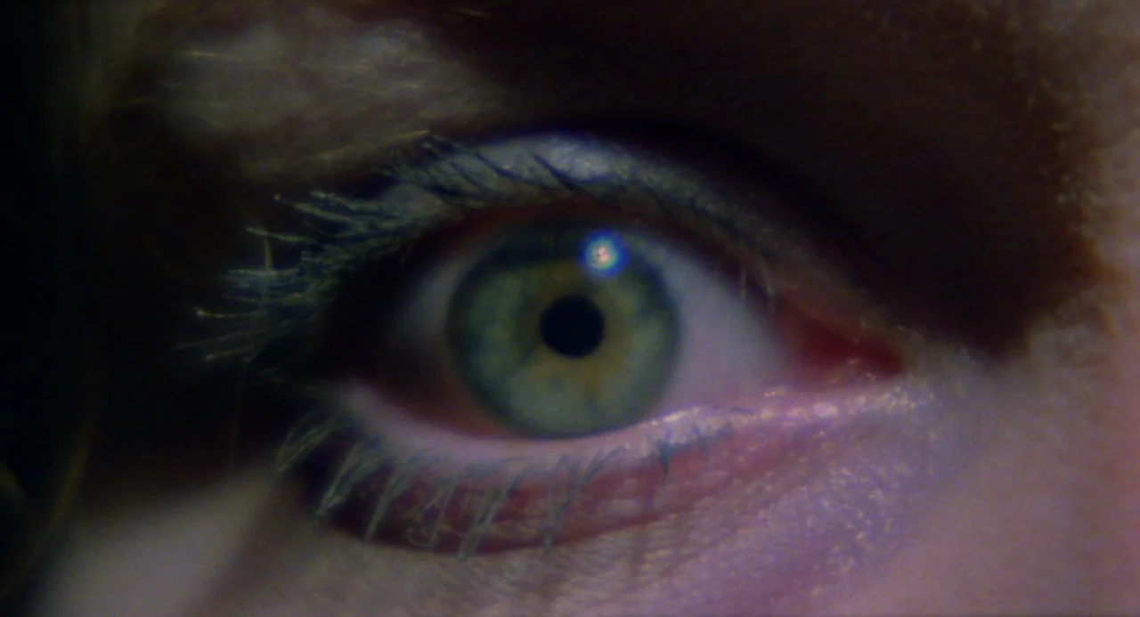 City of the Living Dead (1980) movie still: closeup — A close-up shot focuses on a single human eye against a dark background. The green iris…