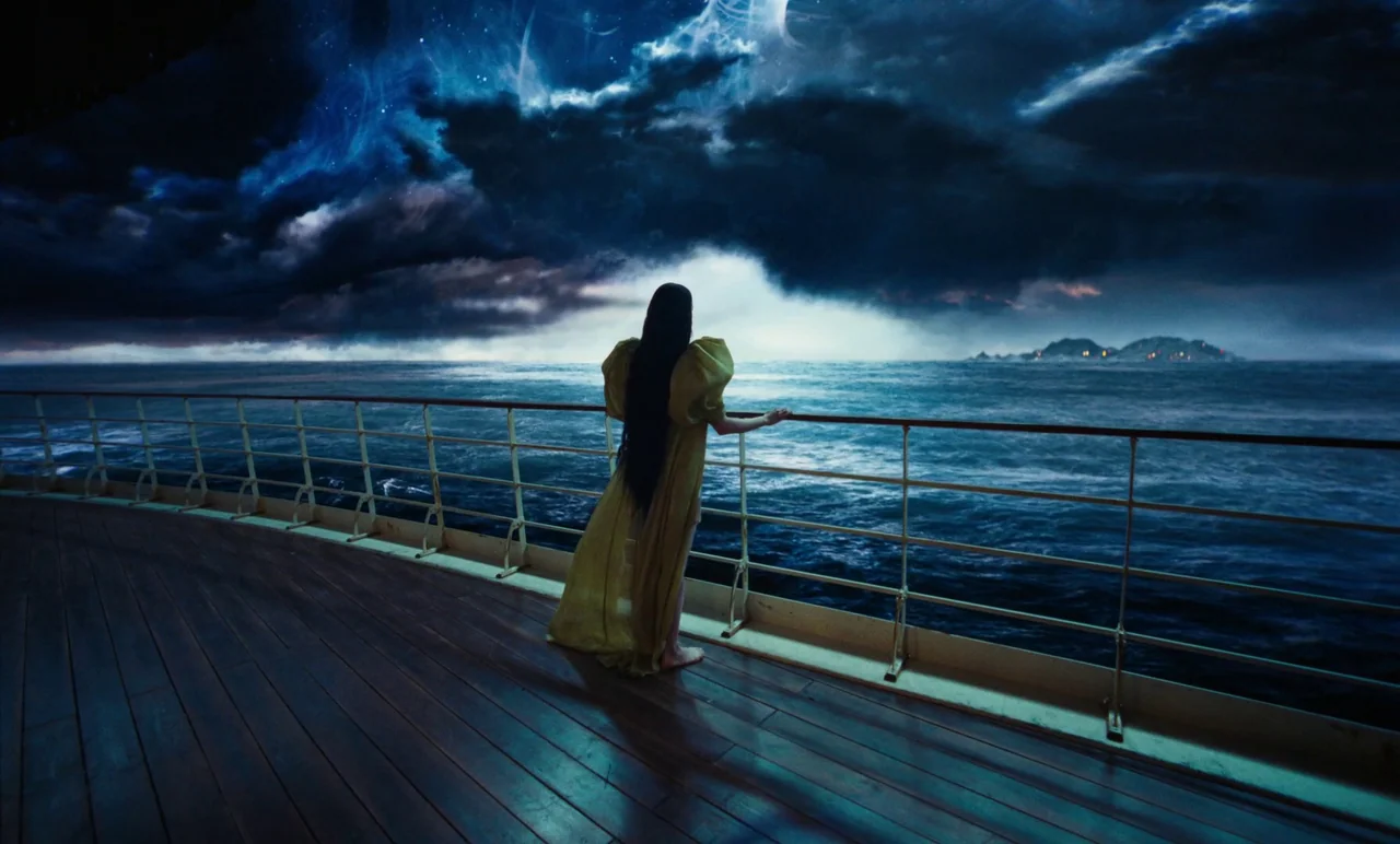 Poor Things (2023) movie still: fullbody — A woman stands on the wooden deck of a large vessel at night. Dark turbulent clouds loom over a vast sea…