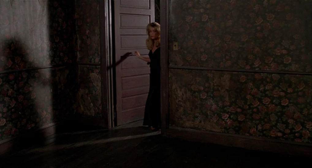 Twin Peaks: Fire Walk With Me (1992) movie still: fullbody — A dimly lit room with dark rose-patterned wallpaper and worn wooden floors. A woman…