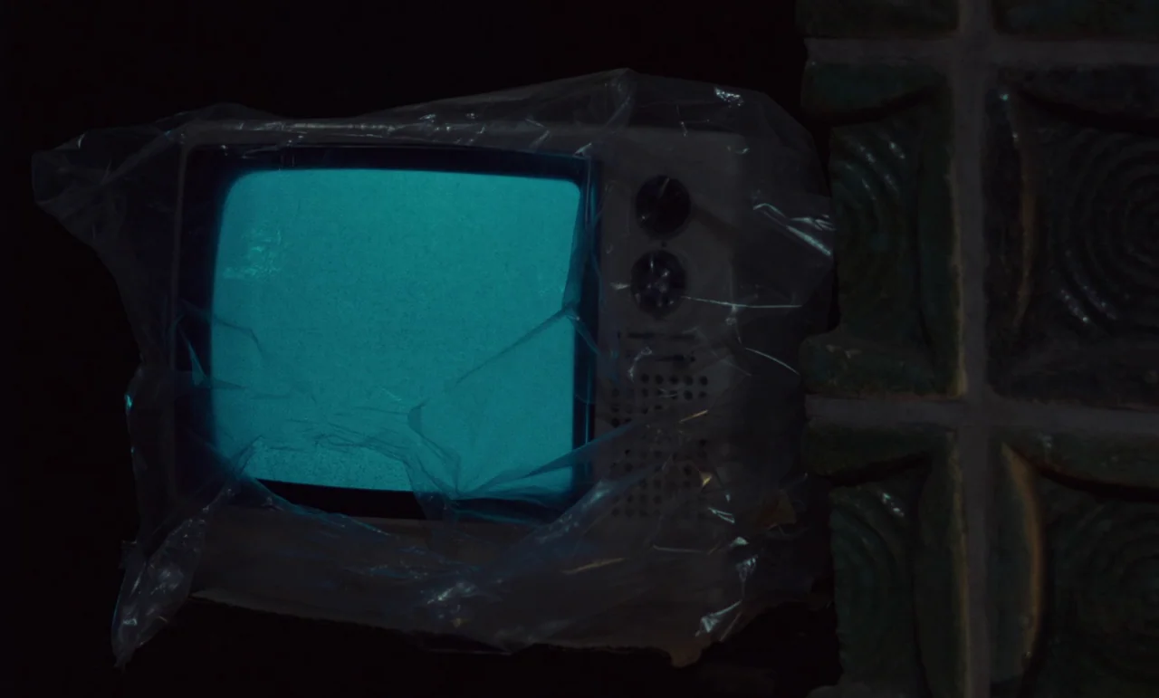 Wrong Move (1975) movie still: closeup — A small vintage television wrapped in thin plastic emits a bright blue light. The device is placed next to…