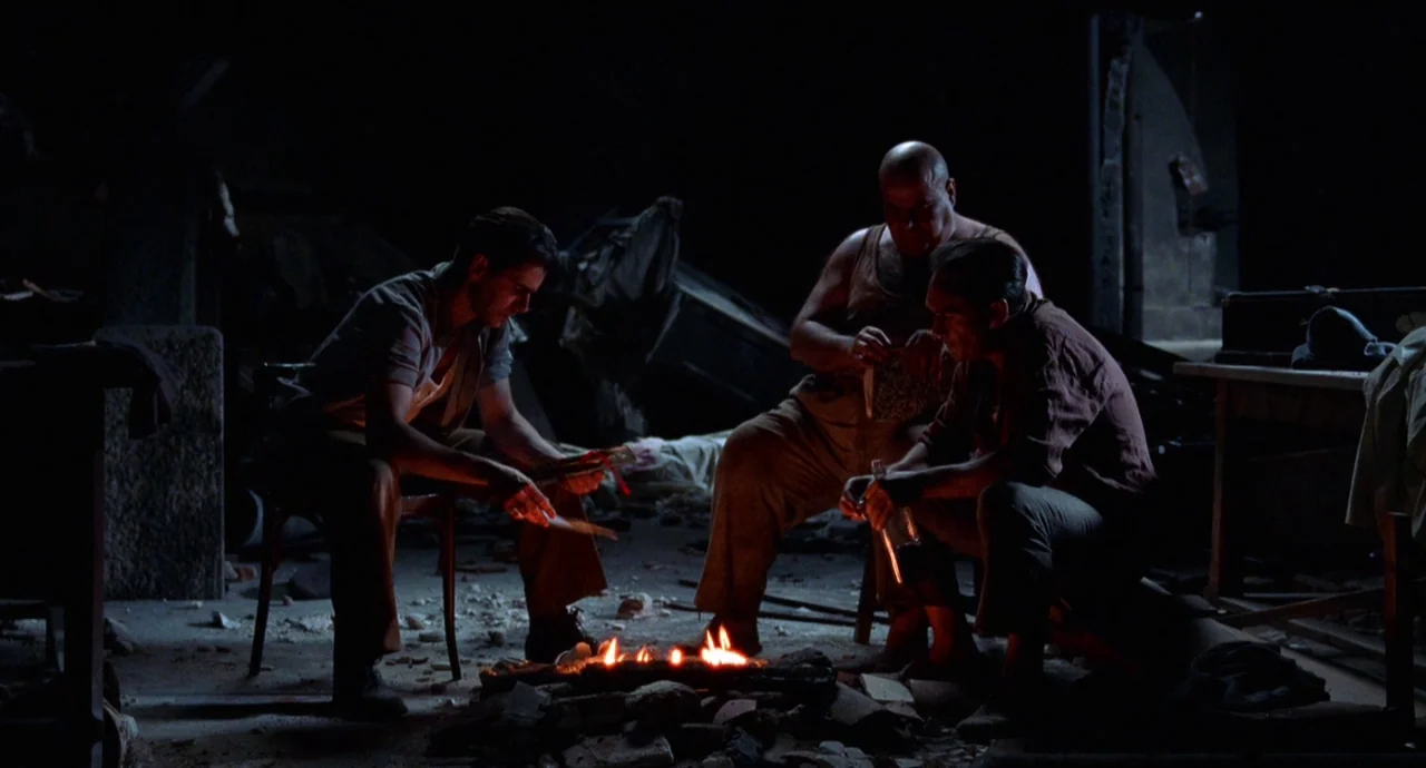 The Devils Backbone (2001) movie still: wide — A dark, rubble-filled interior of a bombed-out building serves as a makeshift shelter. Three men…