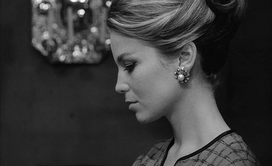 Le Feu Follet (1963) movie still: closeup — A woman in a dark room is framed against a soft out-of-focus background. She stands in profile while…