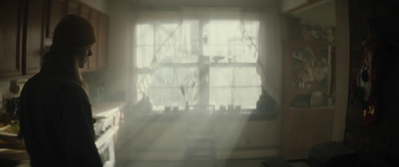 I Think We’re Alone Now (2018) movie still: medium — A dimly lit room with hazy air features a window casting bright light beams. A person stands in…