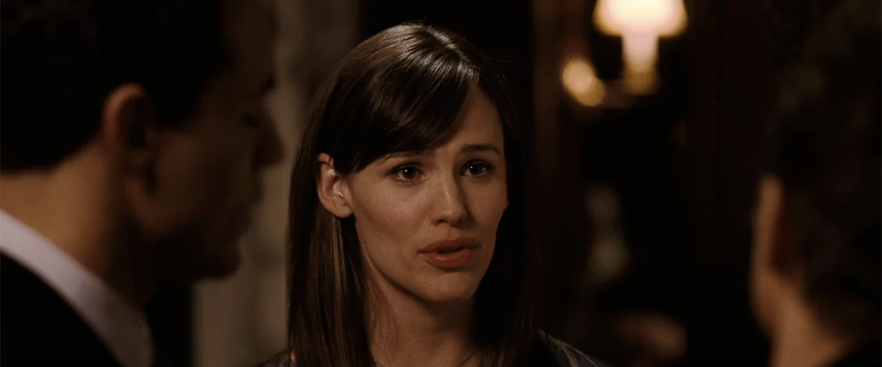 Ghosts of Girlfriends Past (2009) movie still: closeup — An interior ballroom with low lighting and two blurred figures surrounding a central woman.…
