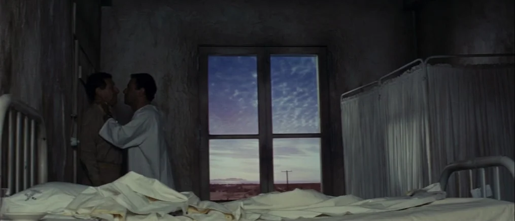 Catch 22 (1970) movie still: wide — A dark hospital ward features unmade beds with white linens and draped privacy curtains. Two men in profile…