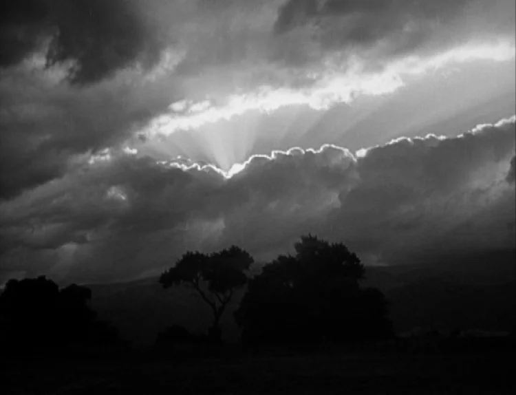 The Lady Eve (1941) movie still: establishing — A field silhouette sits below a dense layer of dark, heavy storm clouds. Sunlight streams through a…