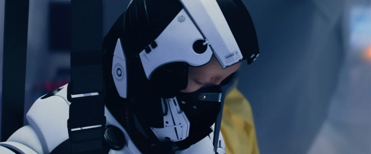 Beyond the Universe (2022) movie still: closeup — A person wears a stylized white and black high-tech helmet inside a cockpit. The individual looks…