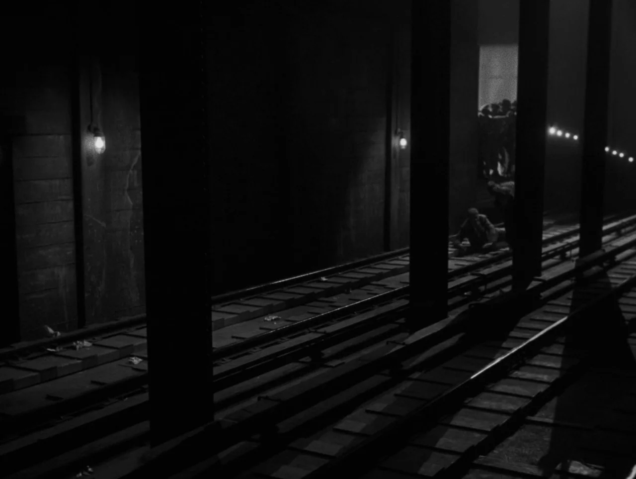 Pickup on South Street (1953) movie still: wide — A subterranean subway track features vertical iron columns and exposed light bulbs. The dark…