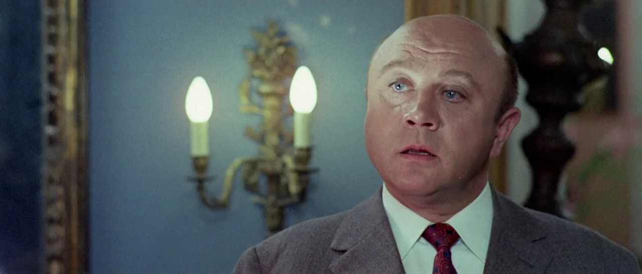 The Bird With The Crystal Plumage (1970) movie still: closeup — An interior wall features a blue surface with an ornamental gold wall sconce. A…