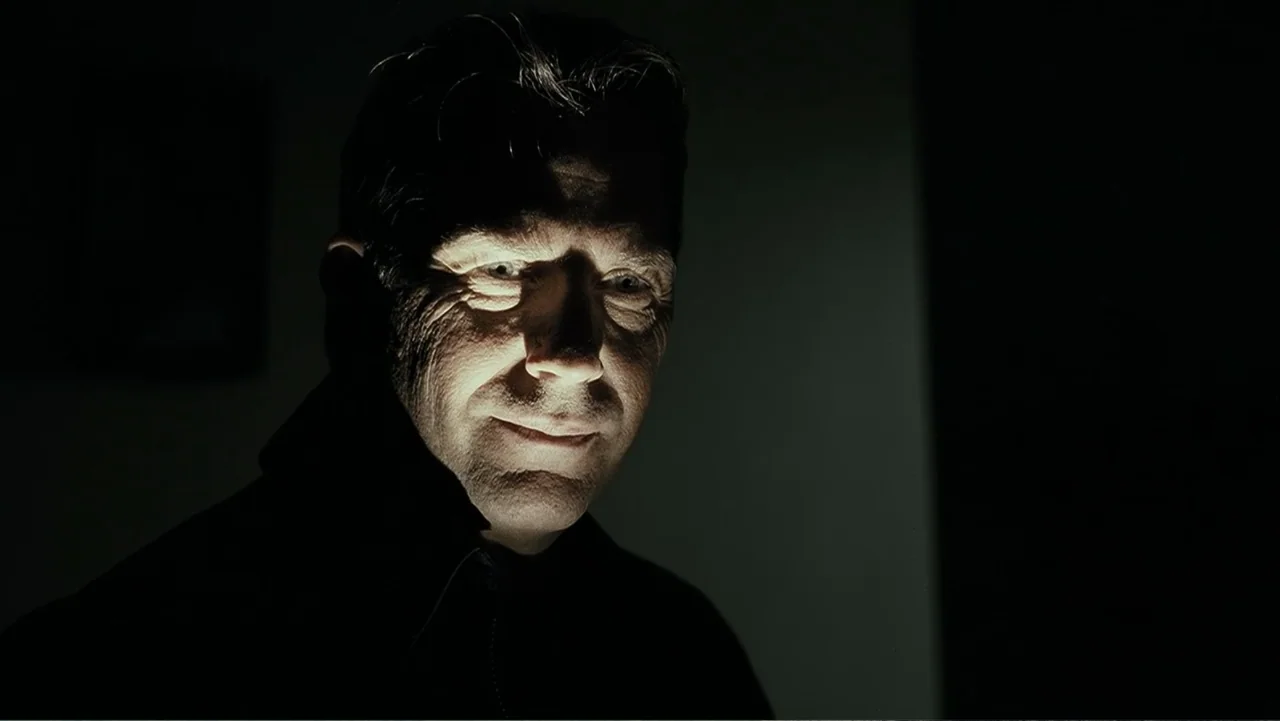 Mr. Brooks (2007) movie still: closeup — An interior space is dark with one side of a man's face lit. A man in his fifties looks toward the camera…