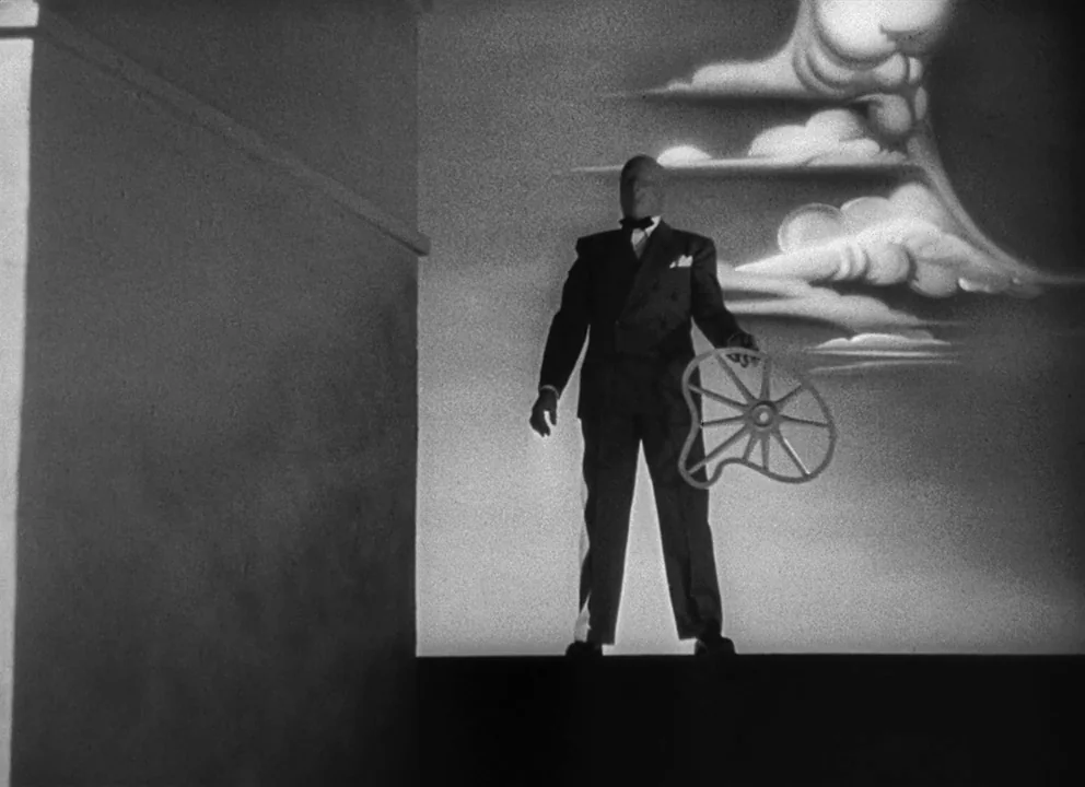 Spellbound (1945) movie still: fullbody — A man in a tuxedo stands on a minimalist soundstage platform. A projection of stylized clouds and a…