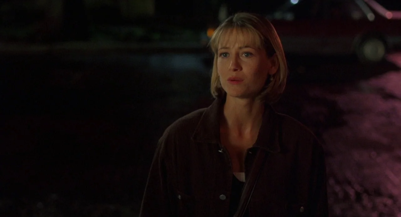 Candyman: Farewell to the Flesh (1995) movie still: medium — A dark, paved area at night with a distant red car in the background. A blonde woman in…