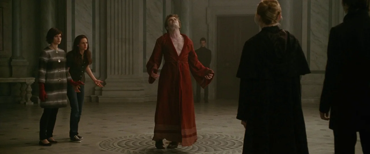 The Twilight Saga: New Moon (2009) movie still: wide — A spacious hall with marble floors and stone pillars in an ancient stone architecture. A man…