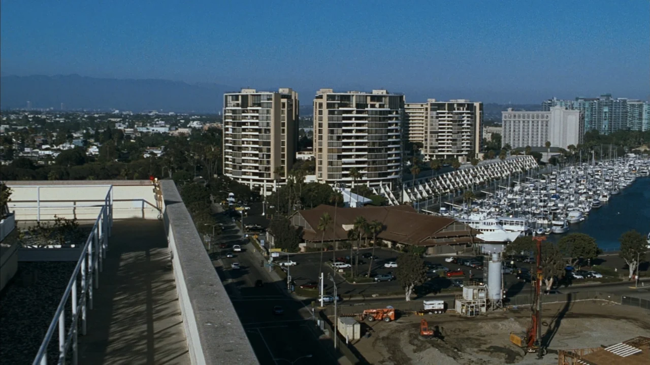 F Valentine's Day (2026) movie still: establishing — An aerial view of a marina with multi-story apartment buildings and a construction site.…