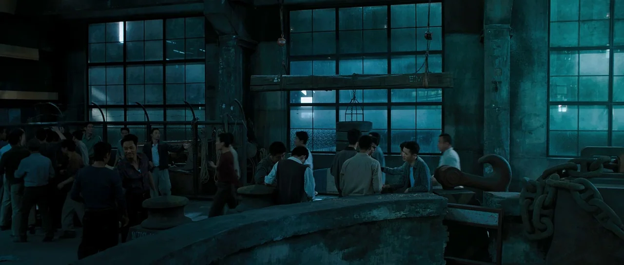 Ip Man 3 (2015) movie still: wide — A dark industrial factory space with large steel-framed windows and concrete structural elements. A group of men…