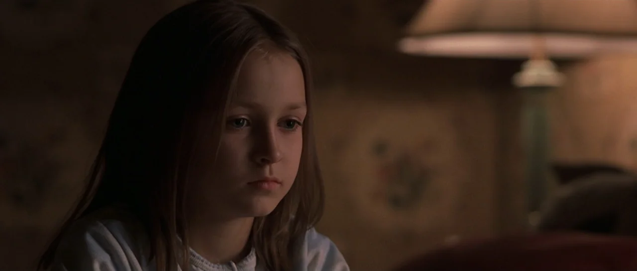 Don't Say a Word (2001) movie still: closeup — A dimly lit room features a child seated in front of a soft light source. The girl looks forward…