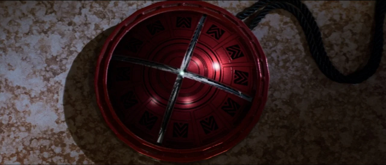 Star Trek: Nemesis (2002) movie still: closeup — A circular red medallion with intricate black markings lies on a marbled light surface. A black…