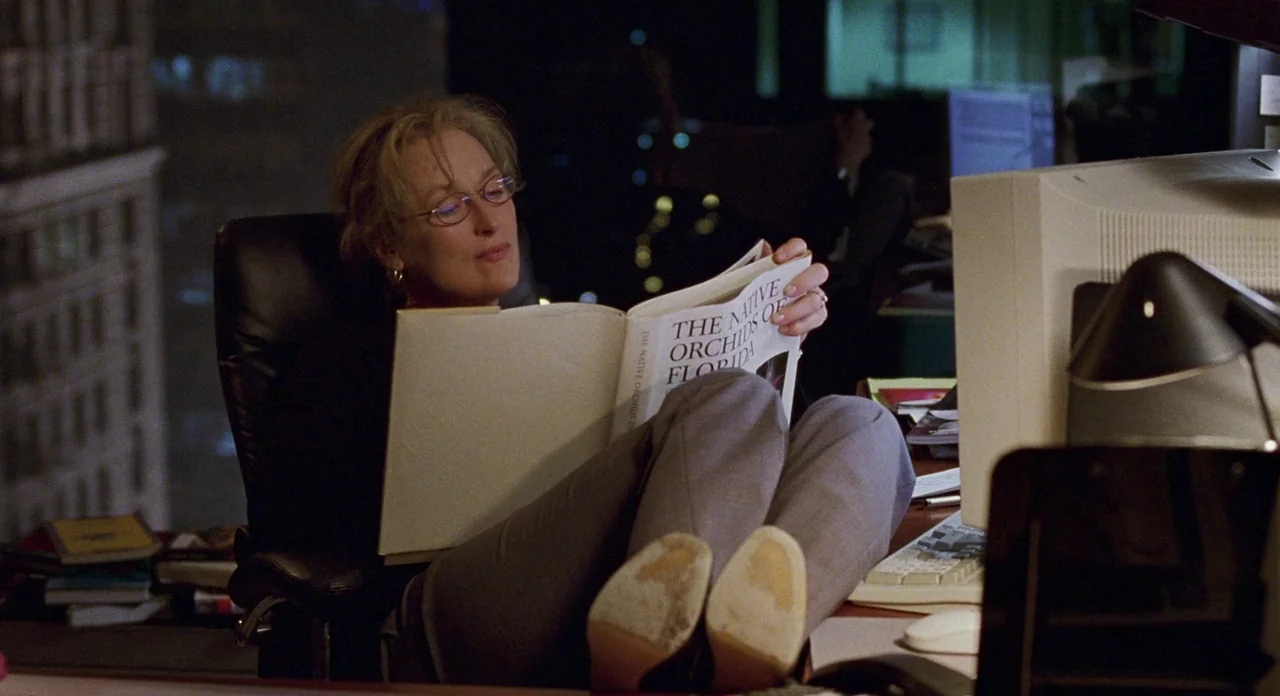 Adaptation (2002) movie still: medium — A dark, modern workspace at night features a large CRT monitor and scattered papers. A woman sits in a…