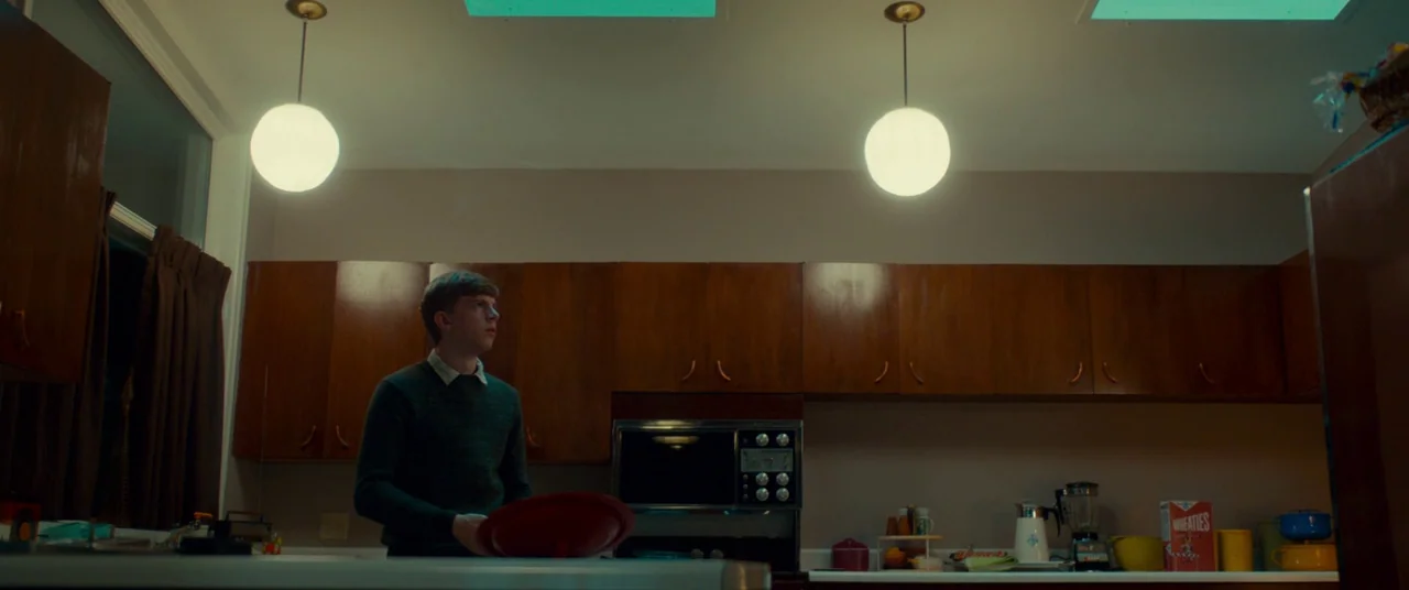 Scary Stories to Tell in the Dark (2019) movie still: medium — A 1970s style kitchen features dark wood cabinets and two spherical pendant lights. A…