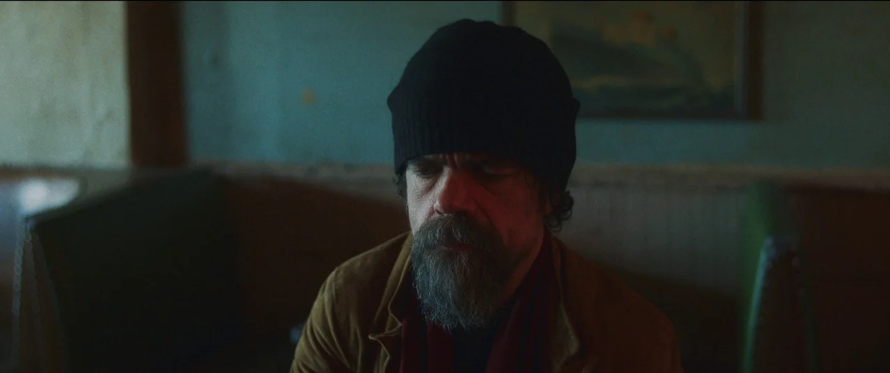 She Came To Me (2023) movie still: medium — A dimly lit restaurant interior with muted green walls and wood paneling. A man with a beard and black…