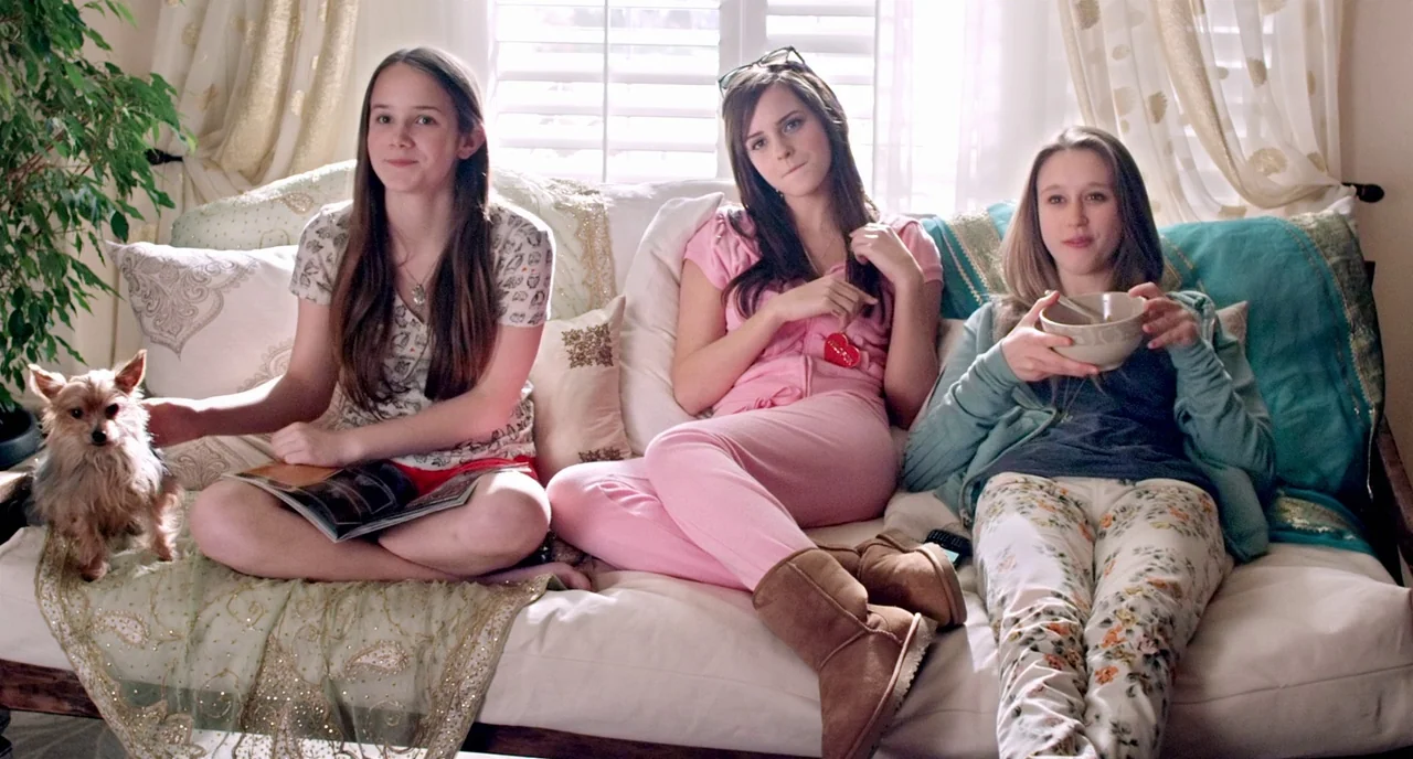 The Bling Ring (2013) movie still: medium — A bright, sunlit room features three young women resting on a plush white couch. They appear relaxed…