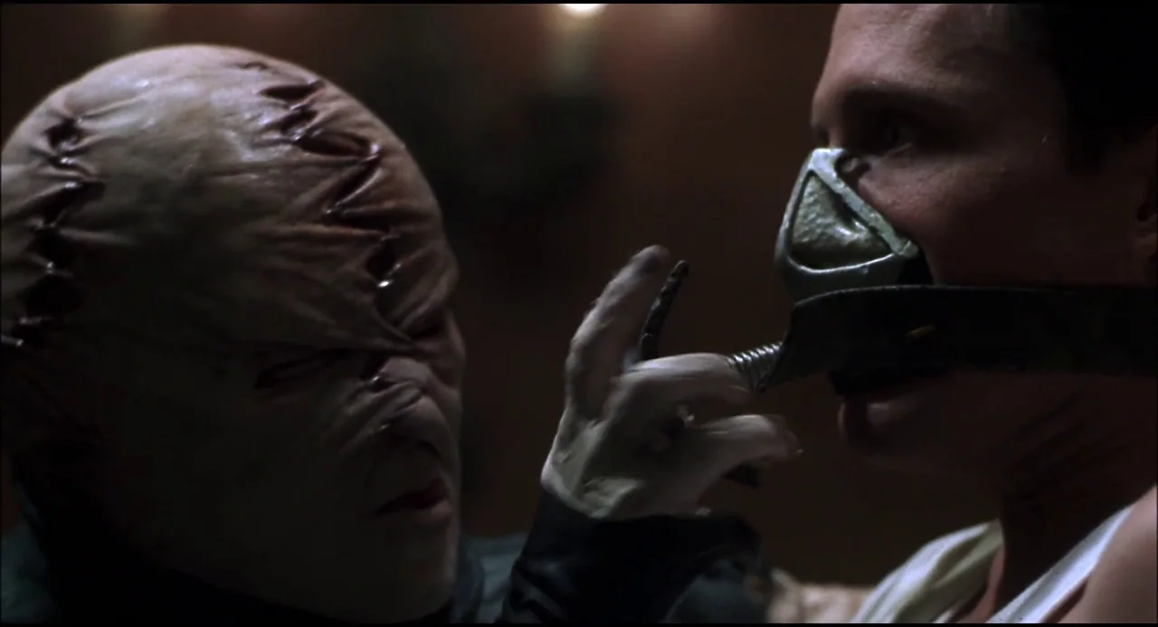 Hellraiser: Hellseeker (2002) movie still: closeup — A dark, dimly lit environment obscures all background details. One person wearing a smooth,…