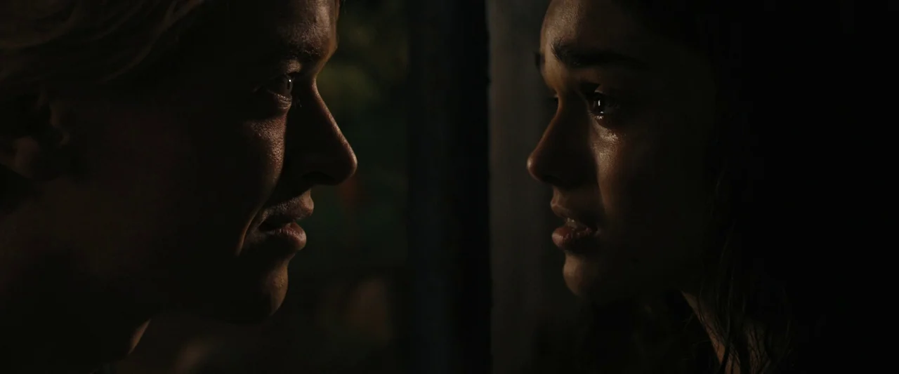 The Hunger Games: The Ballad of Songbirds & Snakes (2023) movie still: closeup — Two individuals stand facing one another in a dark and obscured…
