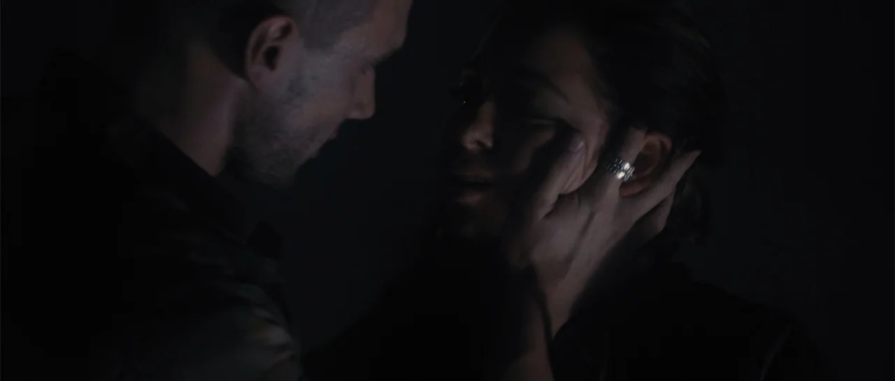 Carrie (2013) movie still: closeup — A dark, dimly lit interior space with minimal ambient light. A man cups the face of a woman with both hands.