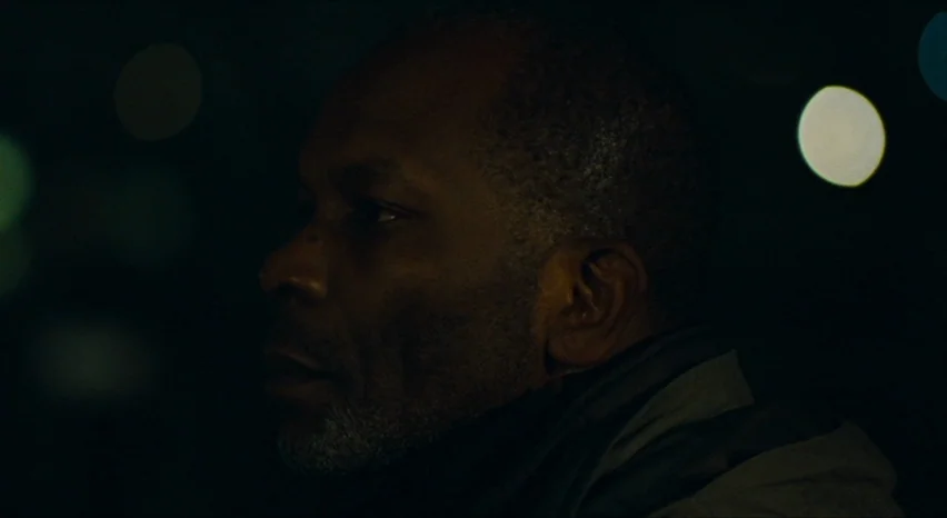 35 Shots of Rum (2008) movie still: closeup — A man stands outdoors at night with blurry, circular bokeh lights in the background. The individual…