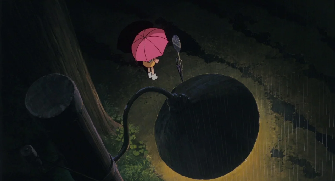 My Neighbour Totoro (1988) movie still: wide — A rainy night scene at a rural bus stop next to a large dark tree. A small character stands holding a…