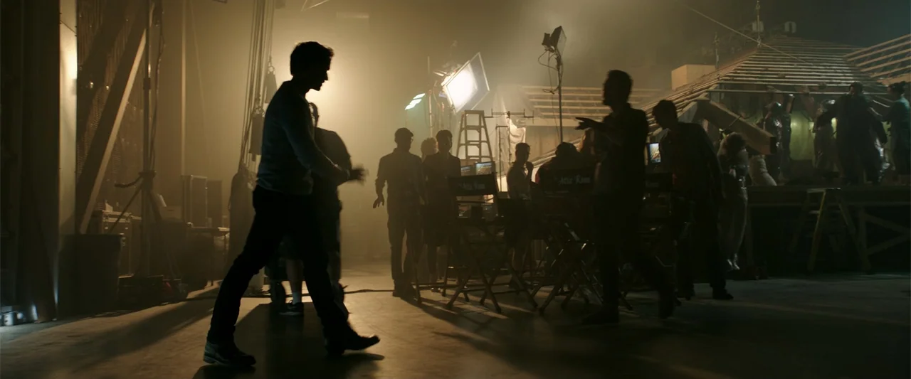 K.G.F: Chapter 2 (2022) movie still: wide — A cluttered soundstage contains production equipment, folding chairs, and a partially constructed wooden…