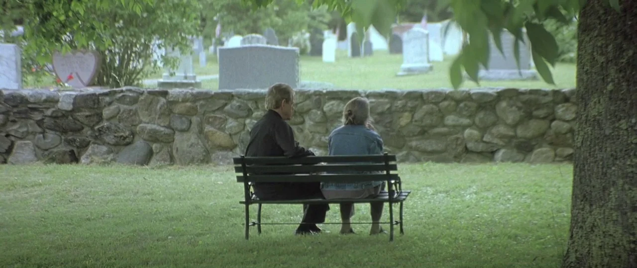 In the Bedroom (2001) movie still: fullbody — A rural cemetery features an old dry-laid stone wall bordering the burial ground. An elderly man and…