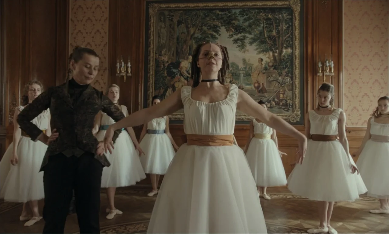 The Ugly Stepsister (2025) movie still: medium — An opulent wood-paneled room features a large framed tapestry hanging on the rear wall. A woman in…