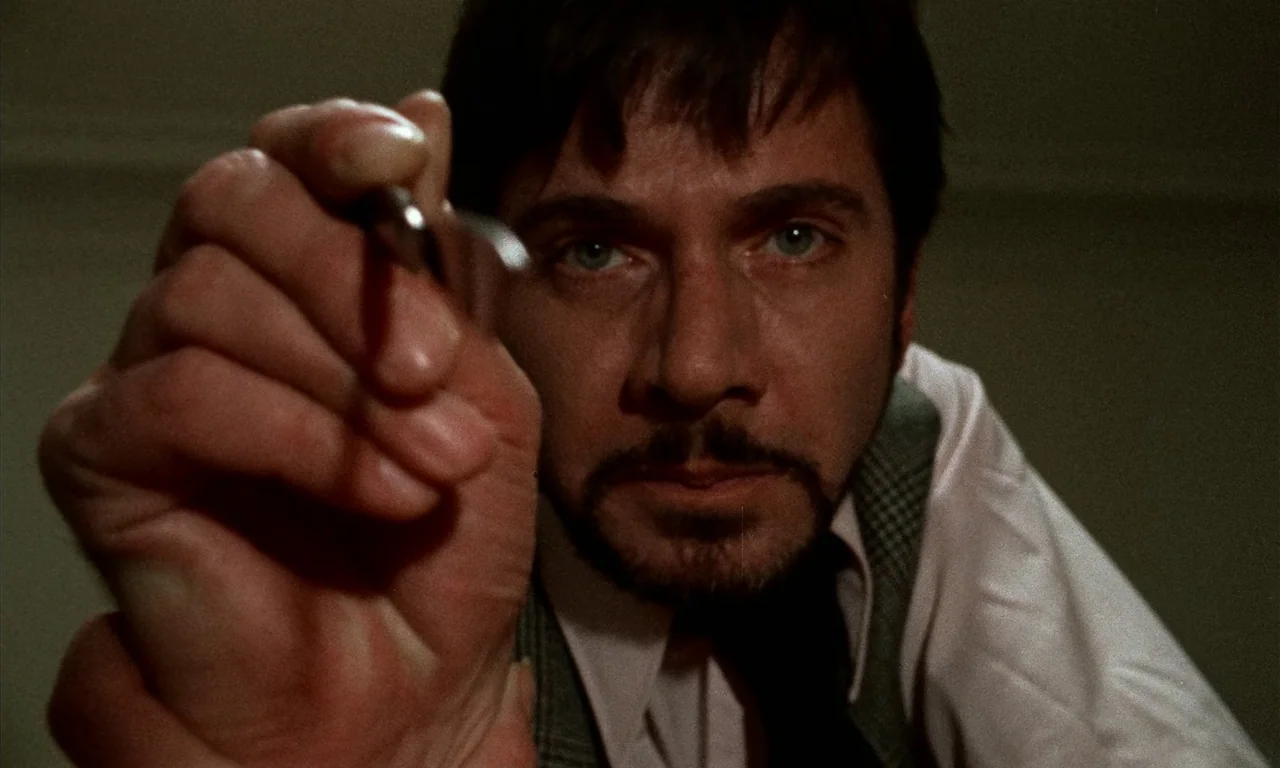 Thriller: A Cruel Picture (1973) movie still: closeup — A man looks directly into the camera lens with a steady gaze. His hand is extended toward…