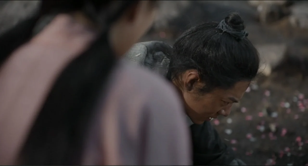 Legends of the Condor Heroes: The Gallants (2025) movie still: medium — A dark, soot-covered outdoor area is strewn with charred debris and colorful…
