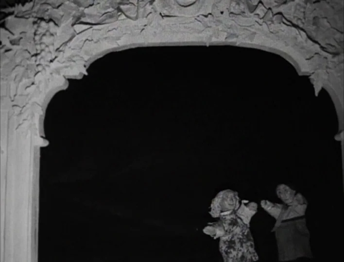 Tales from the Gimli Hospital (1988) movie still: wide — A stone arched opening with intricate carvings frame two hand puppets. The puppets appear…