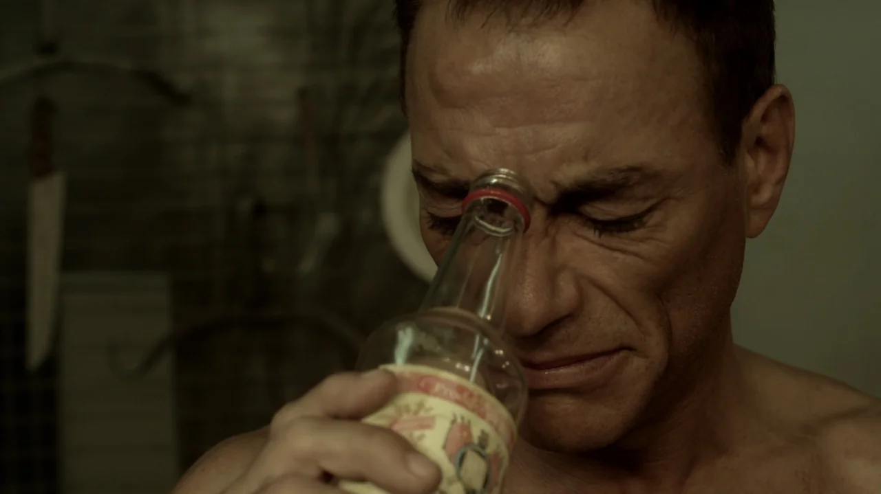6 Bullets (2012) movie still: closeup — A dimly lit room with blurred household items hanging on a tiled wall. A shirtless man presses a small glass…