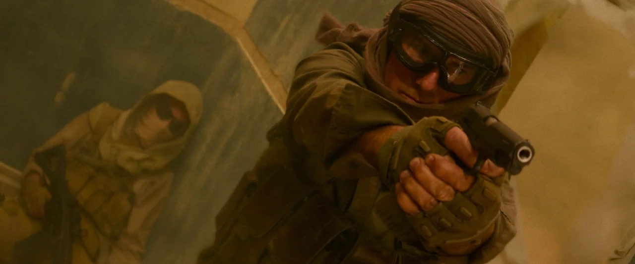 Mission: Impossible – Dead Reckoning Part One (2023) movie still: medium — Two armed individuals in tactical gear occupy a sandy, arid space with…