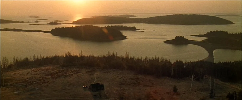 Minority Report movie still: establishing — A golden hour aerial view looks out over a coastal landscape with multiple small islands. A single small…